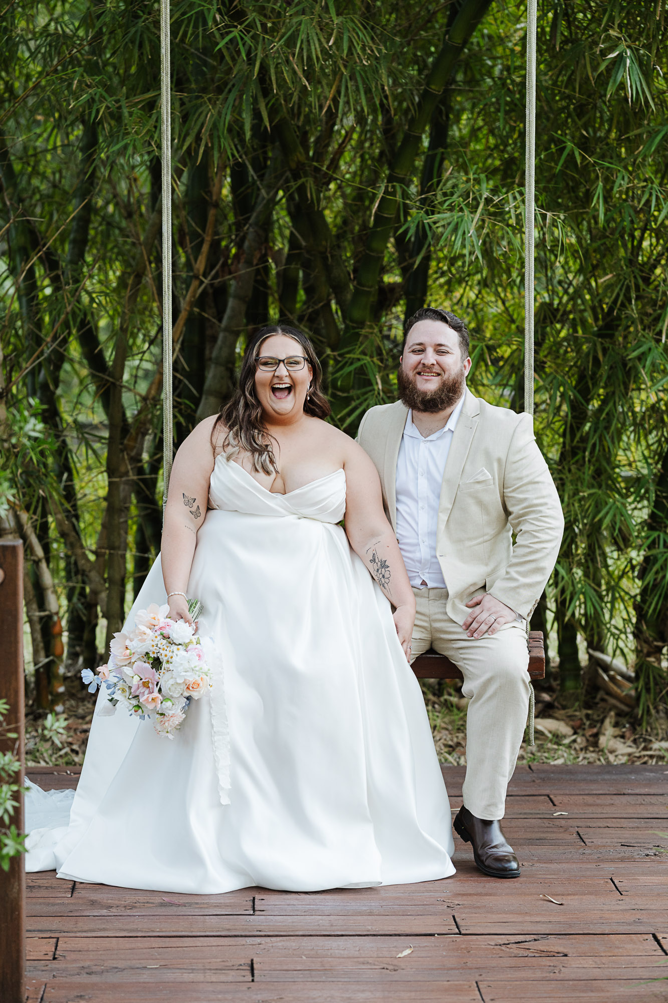 Bride and groom laughing together on a swing at The Prideaux Estate, captured by a Sunshine Coast wedding photographer during their wedding portraits.