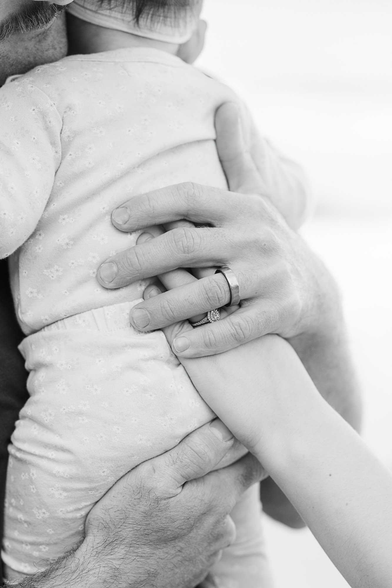 Close-up of a mother and father's hands resting gently on their daughter's back during a family photoshoot in the Sunshine Coast Hinterland.