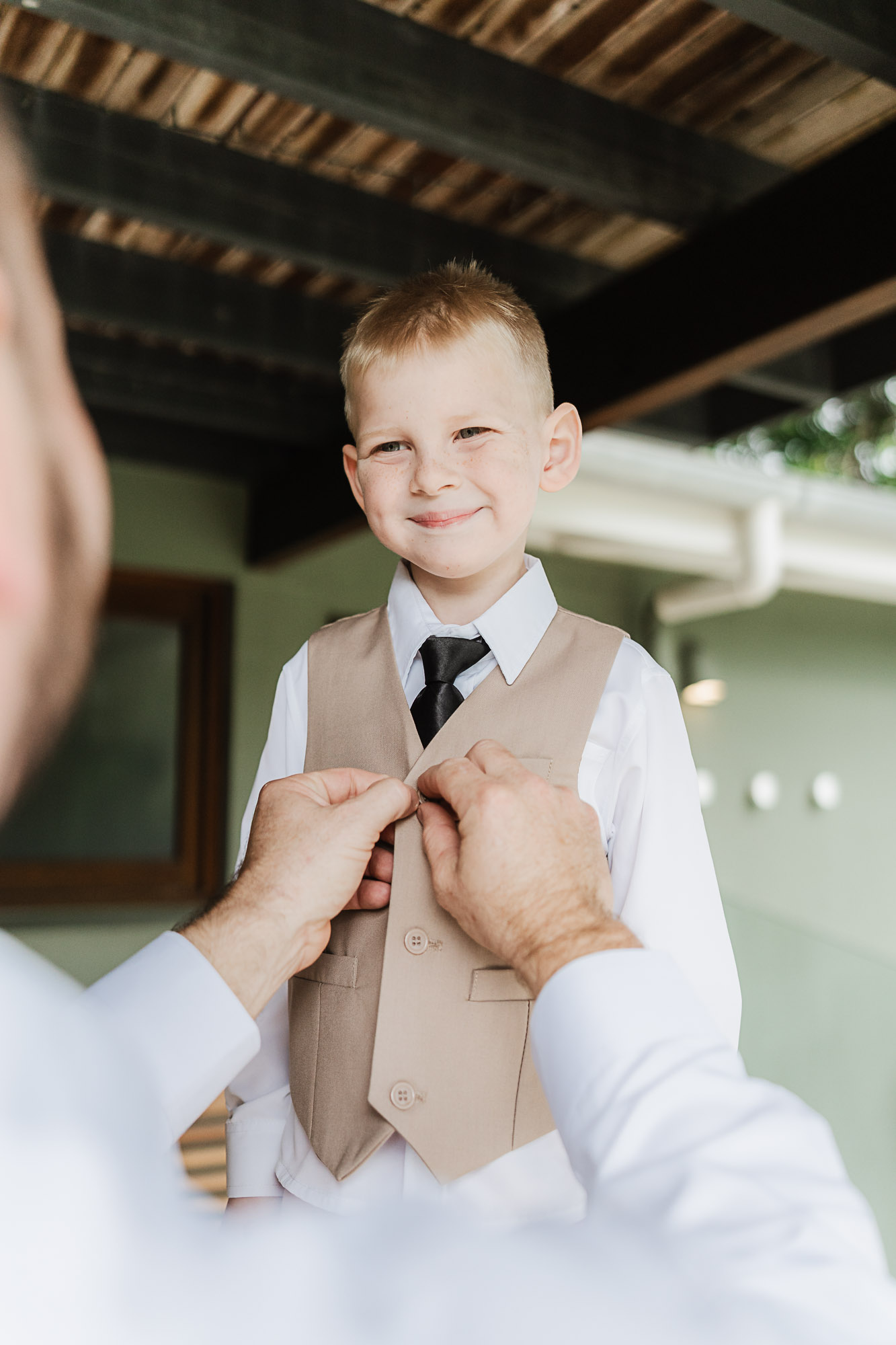 Young son helping his father get ready on his wedding day in Mudjimba, captured by a Sunshine Coast wedding photographer.