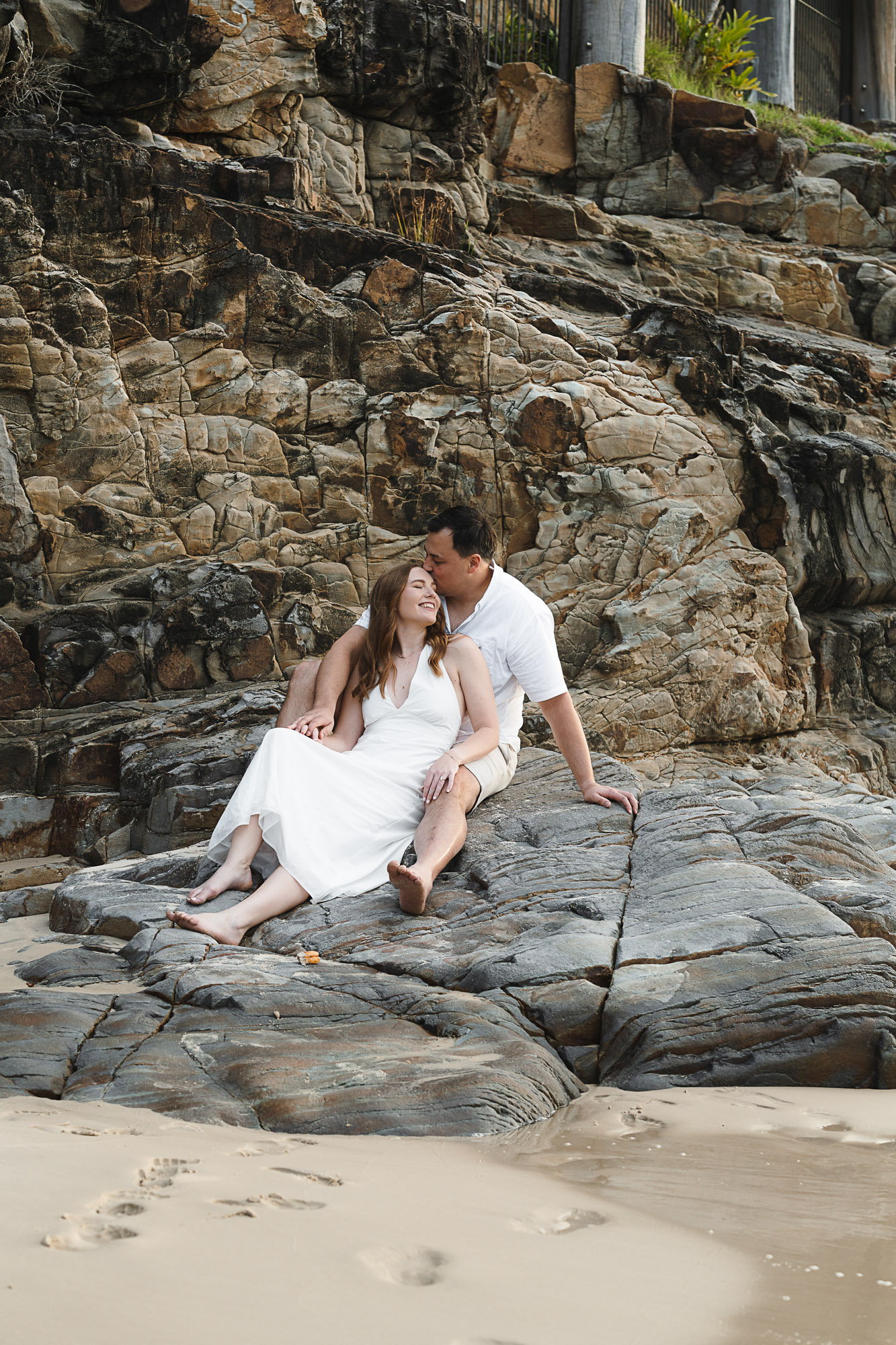 Couple embracing during a golden hour engagement photoshoot at Little Cove Beach in Noosa, captured by a Sunshine Coast engagement photographer.