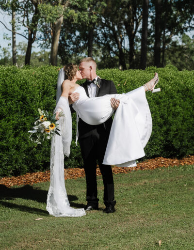 Newly married bride and groom celebrating in Brisbane City, with the groom holding the bride in a joyful candid wedding portrait.