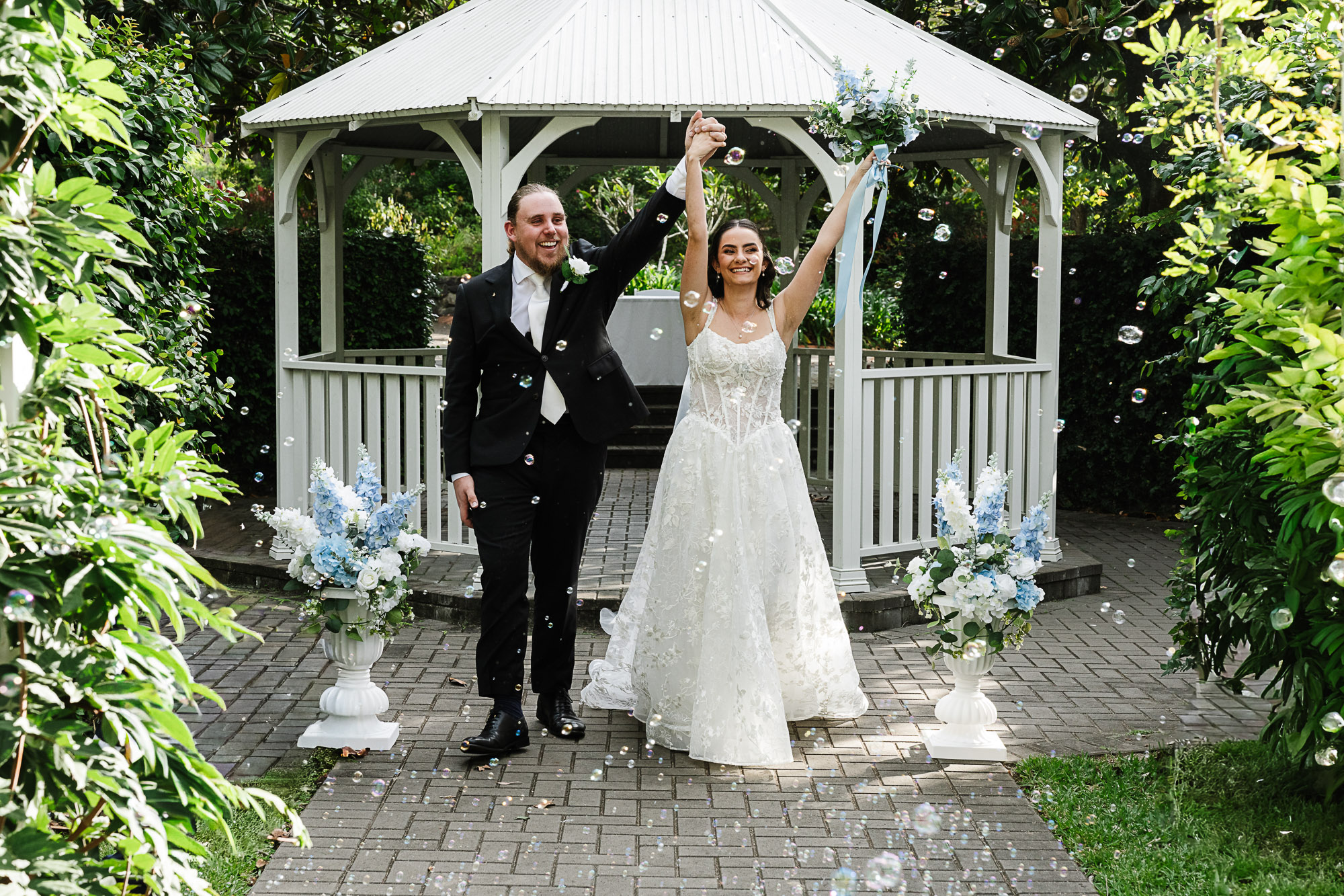Noosa Botanic Gardens Wedding Photographer & Videographer Newlyweds walking back down the aisle after being pronounced husband and wife at Noosa Botanic Gardens, captured by a Sunshine Coast wedding photographer and videographer.
